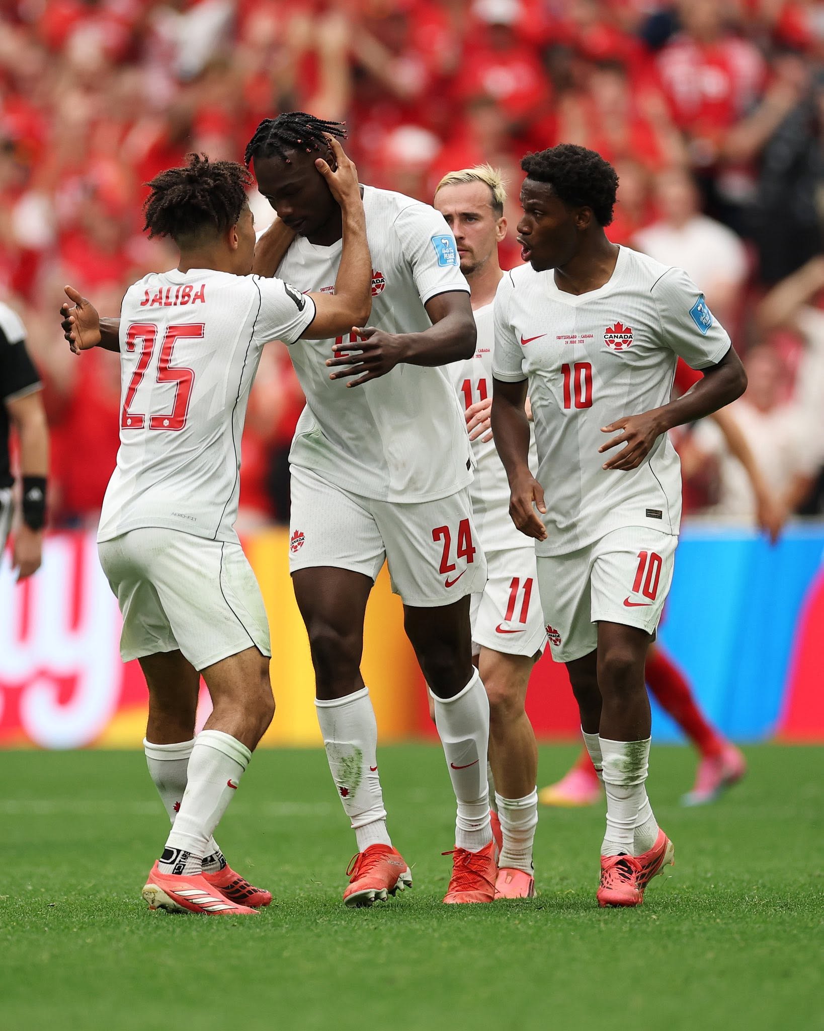 VANCOUVER, BRITISH COLUMBIA - JUNE 24: Promise David #24 of Canada celebrates with teammate Nathan Saliba #25 after scoring his team's first goal during the FIFA World Cup 2026 Group B match between Switzerland and Canada at BC Place Vancouver on June 24, 2026 in Vancouver, British Columbia. (Photo by Jared C. Tilton - FIFA/FIFA via Getty Images)